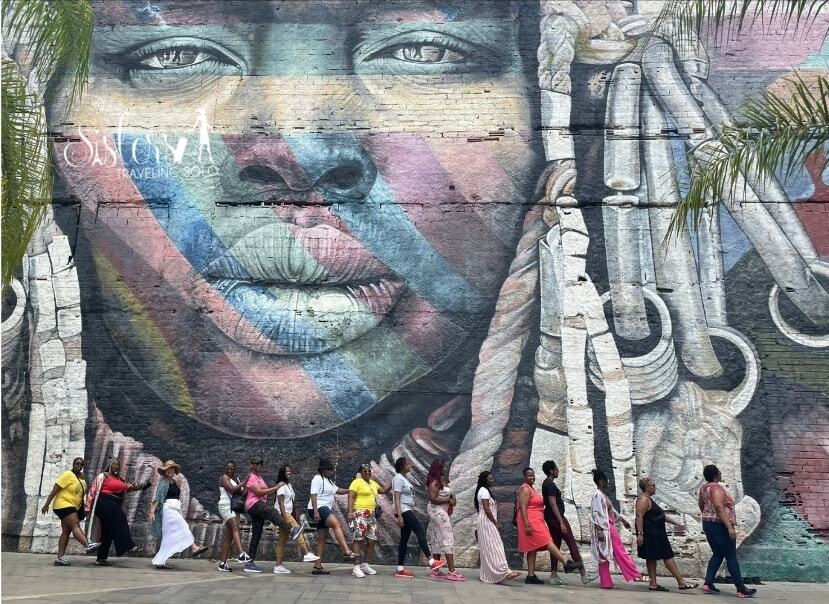 group of women standing in front of a large green door posing for a photo