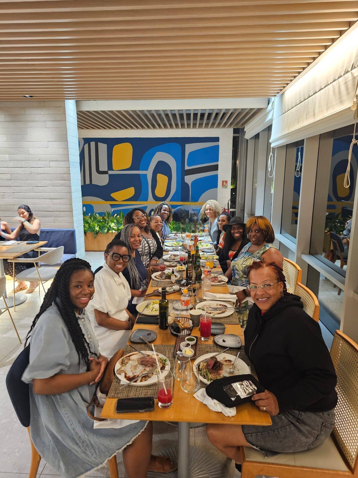 group of women sitting at a lunch table with the view of the ocean in the background