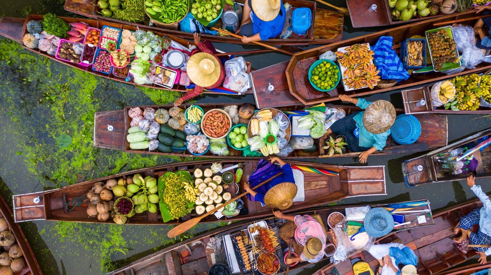 photo of colombian women with fruit on their head walking down the street with stools in their left hand